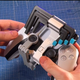 Akaki Kuumeri showcases the directional pad attachment to his PS5 controller mod, which migrates the buttons so they are above the face buttons.